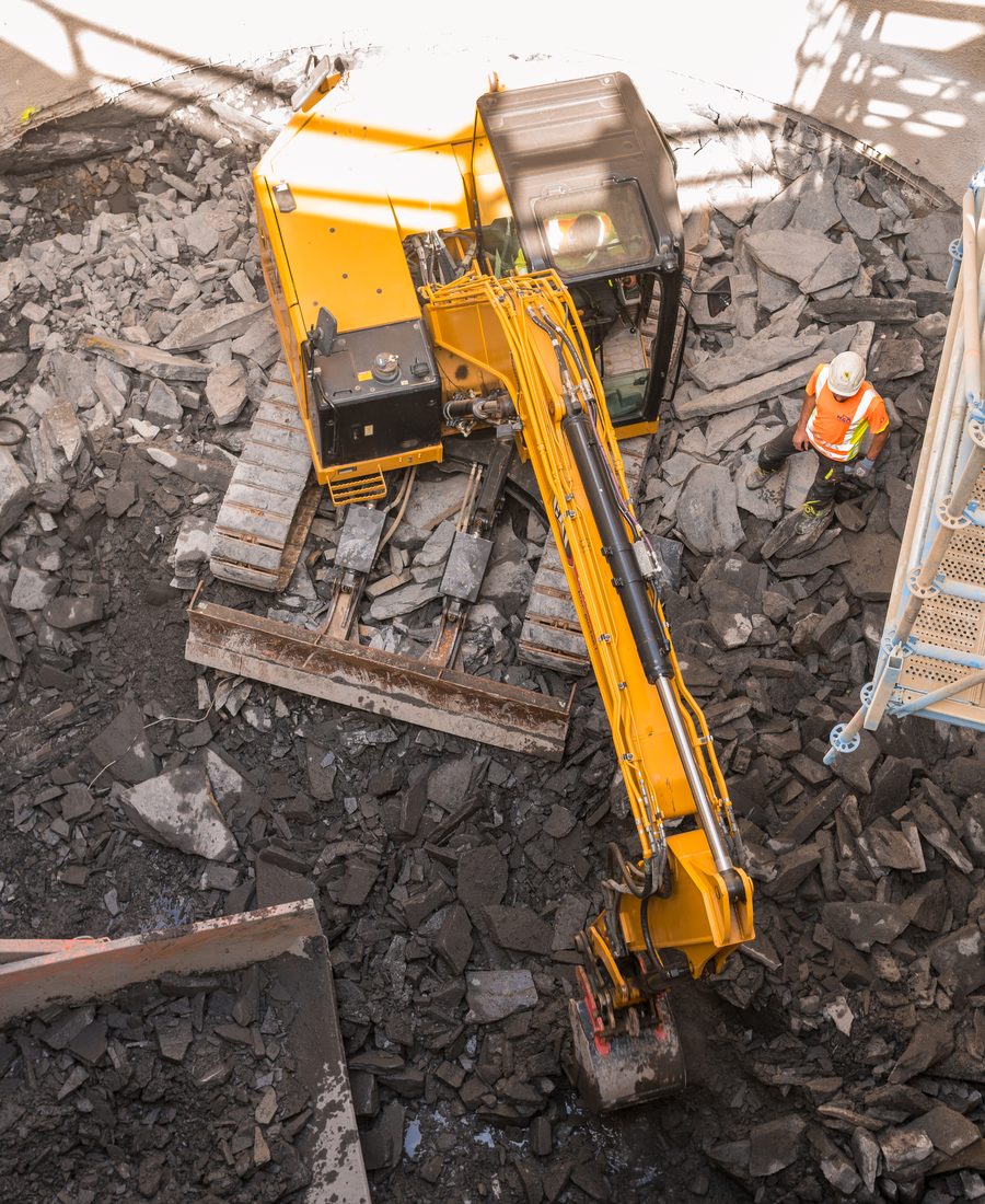 Bagger mit Hydraulikhammer beim Aufstemmen der Betonsohle